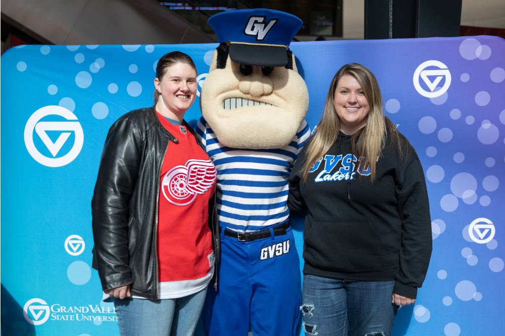 Two alumnae pose with Louie the Laker at the Detroit Red Wings GVSU Night